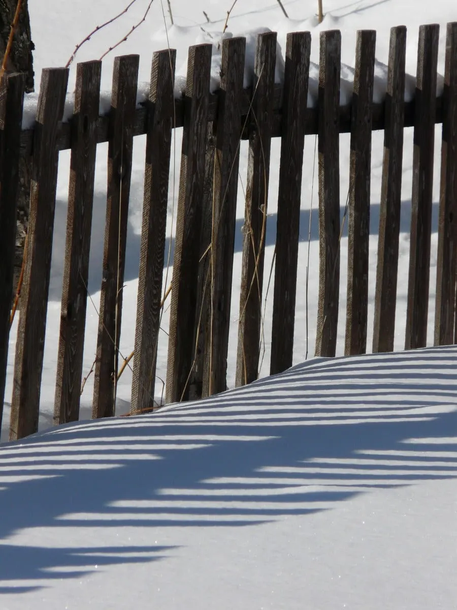 A fence half buried in deep snow